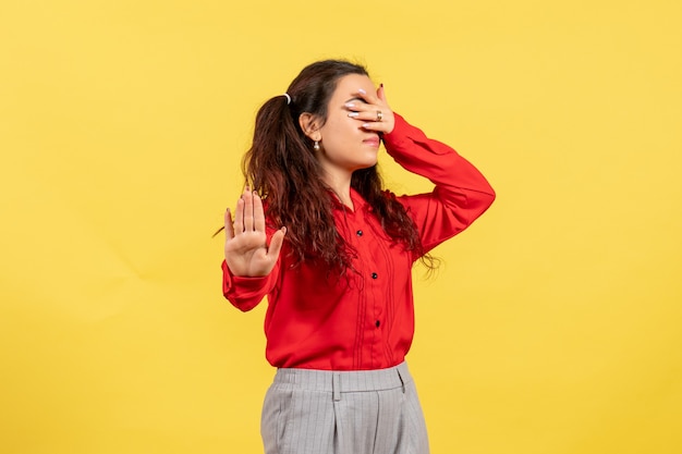 niña en blusa roja que cubre su rostro en amarillo