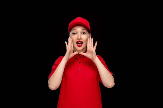 Niña bonita del día de la camisa roja pidiendo ayuda con una gorra roja con camisa y lápiz labial brillante