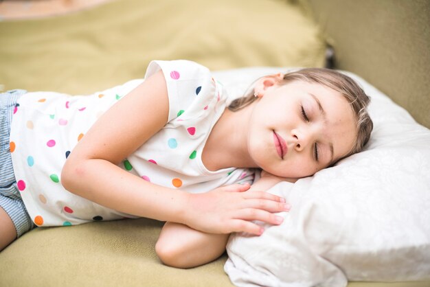 Niña bonita durmiendo en la cama acogedora