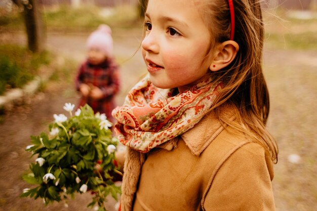 La niña bonita mantiene un ramo y se encuentra en el parque