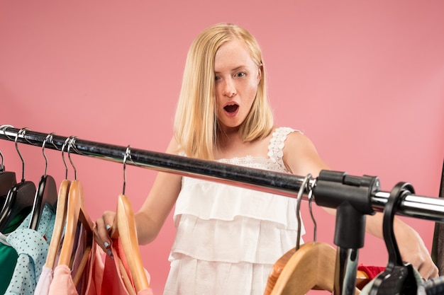 La niña bonita mirando vestidos y probándose mientras elige en la tienda