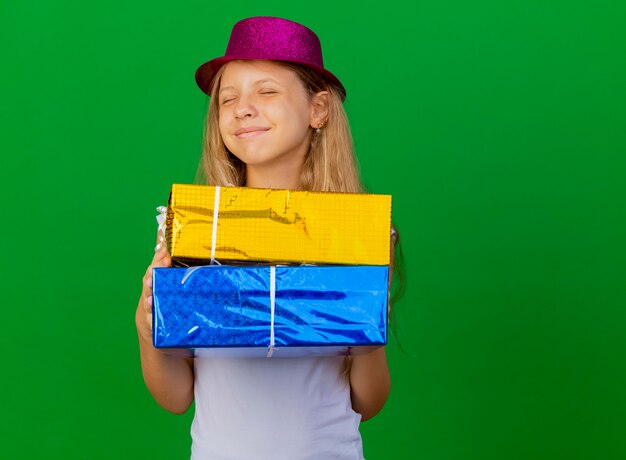 Niña bonita con sombrero de fiesta con cajas de regalo