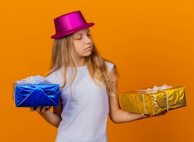 Niña bonita con sombrero de fiesta con cajas de regalo