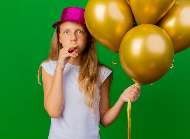 Niña bonita con sombrero de fiesta con montón de globos