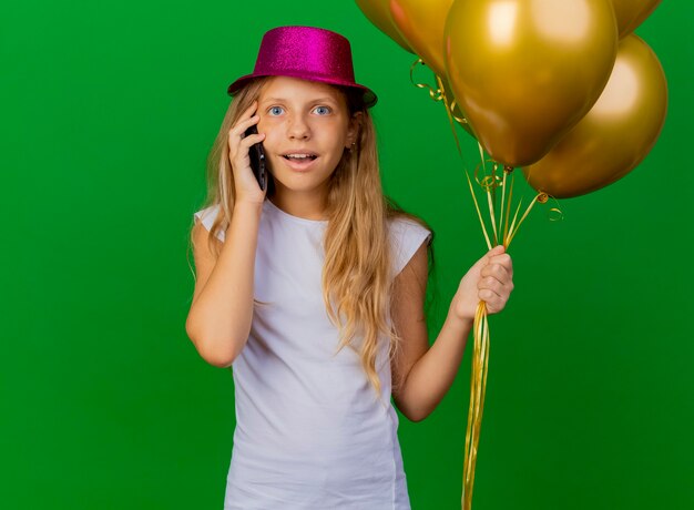 Niña bonita con sombrero de fiesta con smartphone