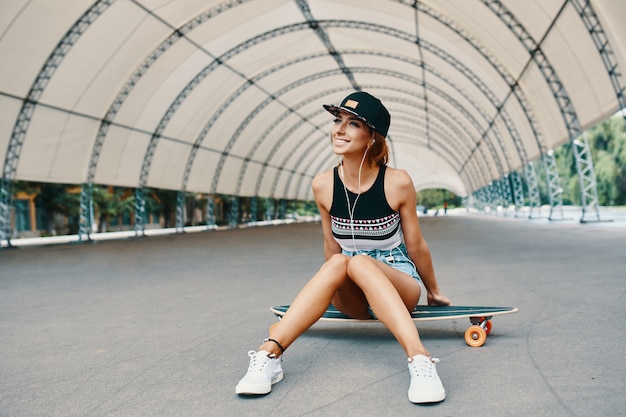 Niña bonita sonriente con un longboard