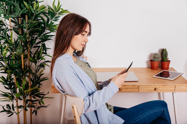 Foto gratuita niña bonita con teléfono en la mesa