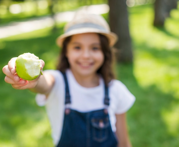 Niña borrosa sosteniendo una manzana verde