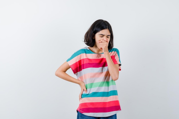 Niña bostezando en camiseta y con sueño, vista frontal.