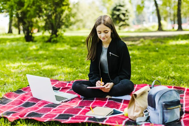 Niña buena escribiendo y estudiando en el parque