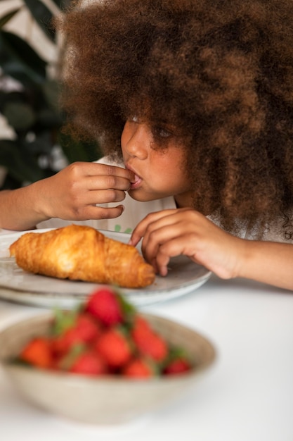 Niña con cabello rizado desayunando