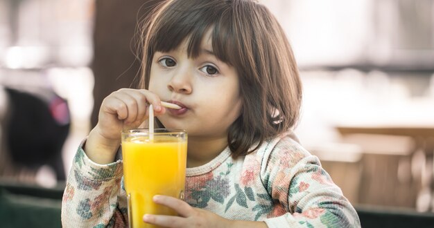 Niña en un café bebiendo jugo