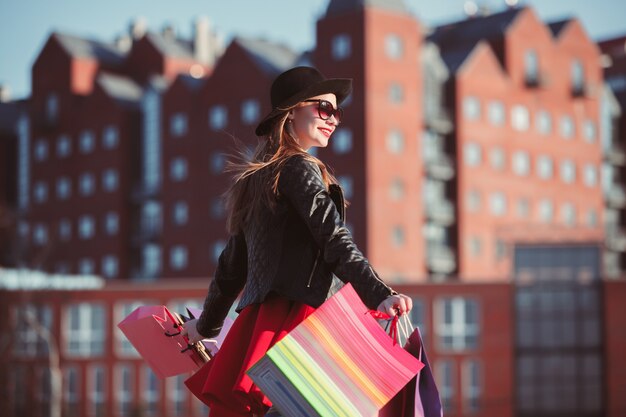 La niña caminando con bolsas de compras en las calles de la ciudad en un día soleado