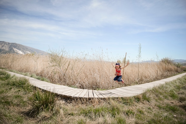 Niña caminando por un camino de tablas de madera en un humedal en Padul, Granada, Andalucía, España