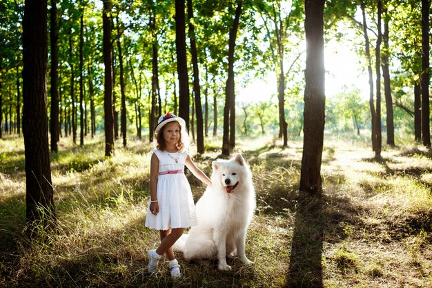 Niña caminando, jugando con el perro en el parque al atardecer.