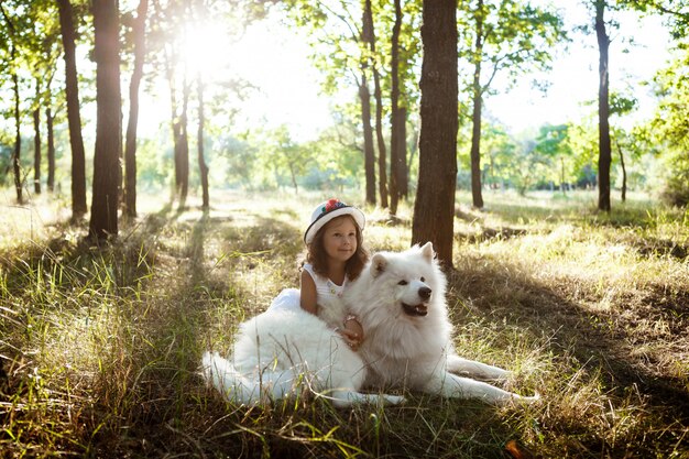 Niña caminando, jugando con el perro en el parque al atardecer.