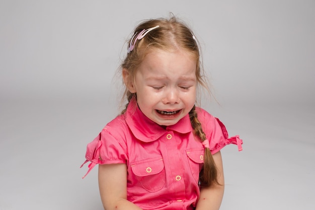 Foto gratuita niña con camisa rosa mirando a un lado y llorando sobre un fondo aislado niño triste asustado gritando en el estudio niño infeliz llorando concepto de ofensa de violencia e infancia