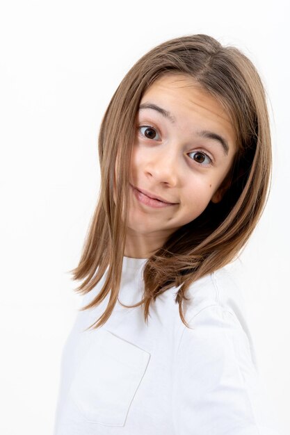 Niña con una camiseta blanca sonríe alegremente en un fondo blanco aislado