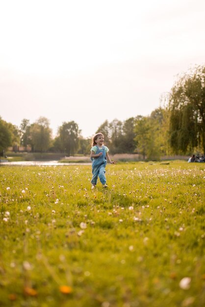 Niña en un campo de diente de León, al atardecer, niño feliz emocional.