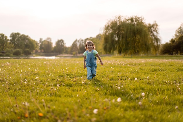 Niña en un campo de diente de León, al atardecer, niño feliz emocional.