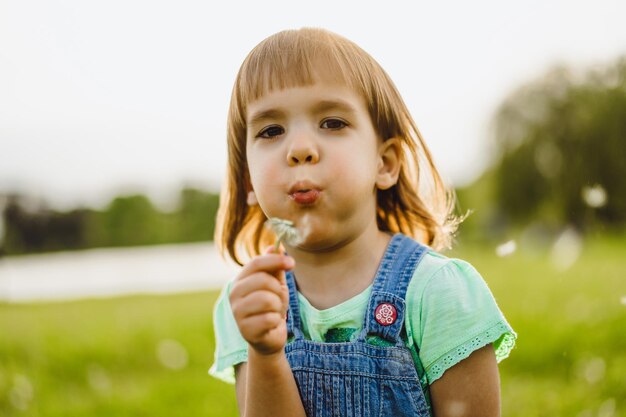 Niña en un campo de diente de León, al atardecer, niño feliz emocional.