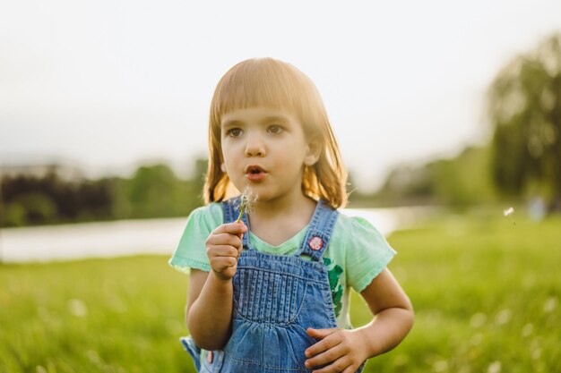 Niña en un campo de diente de León, al atardecer, niño feliz emocional.