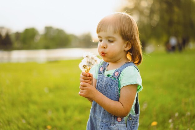 Niña en un campo de diente de León, al atardecer, niño feliz emocional.