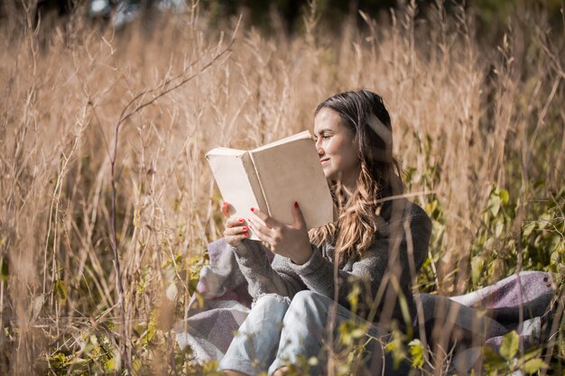 Niña en un campo leyendo un libro