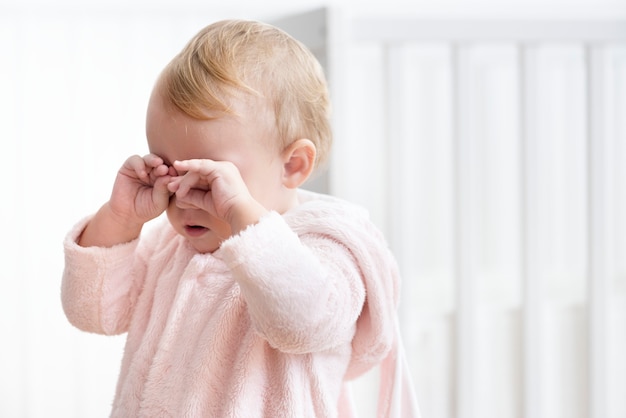 Niña cansada llorando y frotándose los ojos