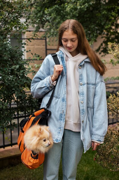 Niña cargando cachorro en bolsa vista frontal