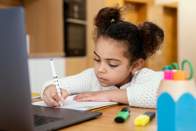 Niña en casa durante la escuela en línea con laptop