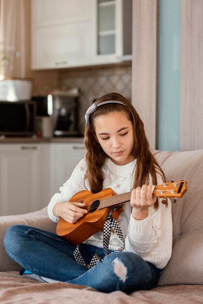 Niña, en casa, tocar la guitarra