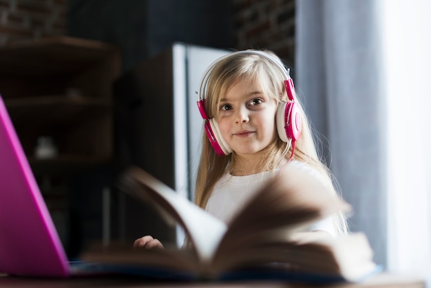 Foto gratuita niña con cascos detrás de libro