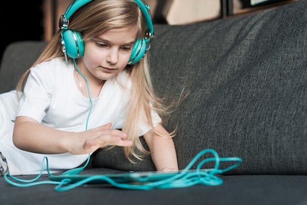 Niña con cascos de música y tablet