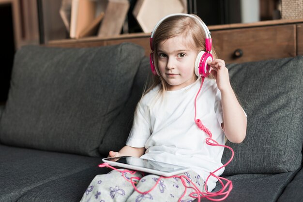 Niña con cascos en sofá