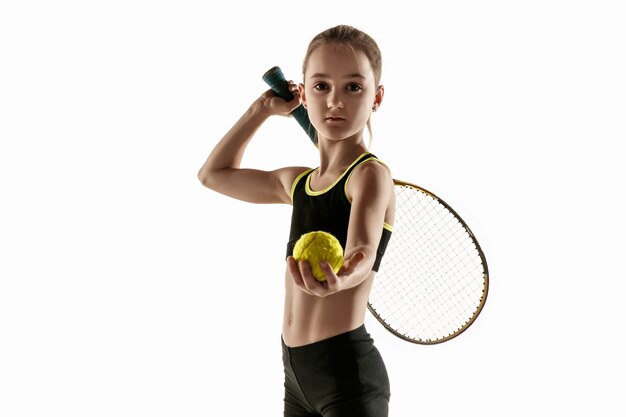 Niña caucásica jugando al tenis aislado en la pared blanca