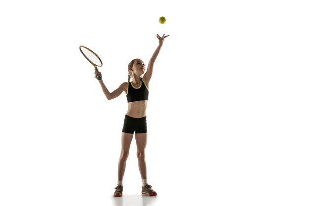 Niña caucásica jugando al tenis aislado en la pared blanca