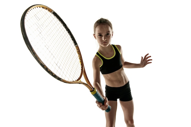 Niña caucásica jugando al tenis sobre fondo blanco.