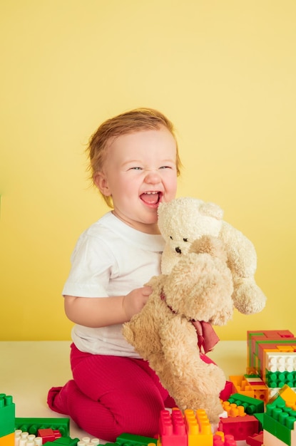 Niña caucásica, niños aislados sobre fondo amarillo de estudio. Retrato de niño lindo y adorable, bebé jugando y riendo.