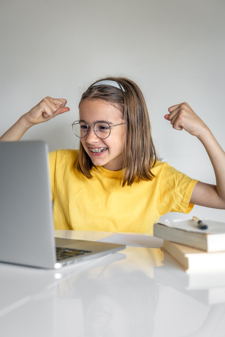 Foto gratuito niña caucásica sonriente haciendo una llamada de video en una clase remota usando una computadora portátil