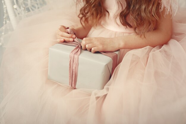 Niña cerca del árbol de navidad en un vestido rosa