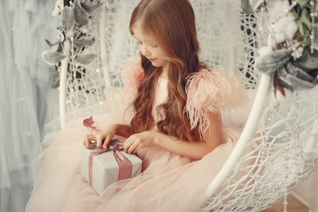 Niña cerca del árbol de navidad en un vestido rosa