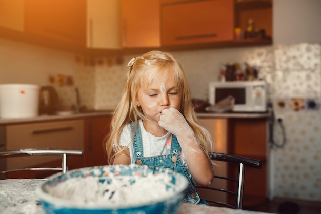 Niña chupándose un dedo lleno de harina