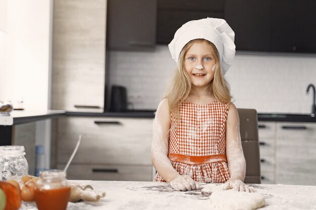 Niña cocina la masa para galletas