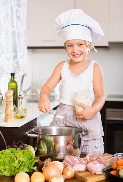 Niña cocinando con carne