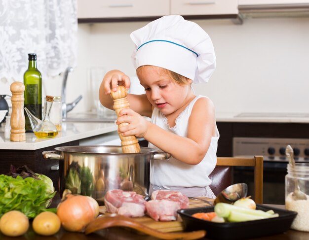 Niña cocinando con carne