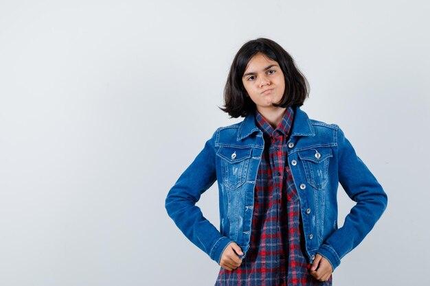 Niña cogidos de la mano en la cintura en camisa, chaqueta y mirando pensativo, vista frontal.