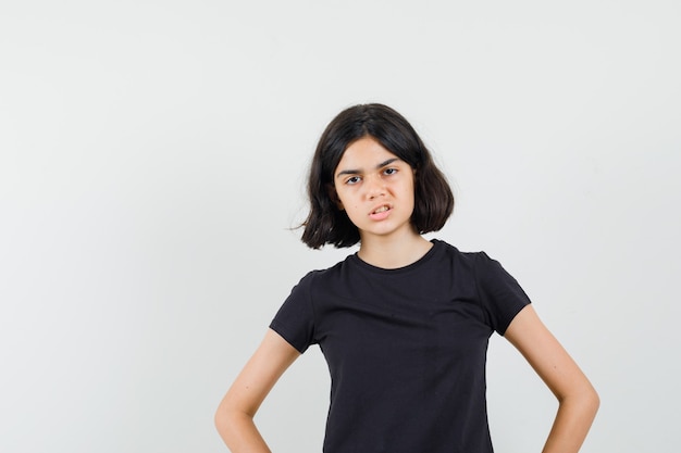 Foto gratuita niña cogidos de la mano en la cintura en camiseta negra y con enojo. vista frontal.