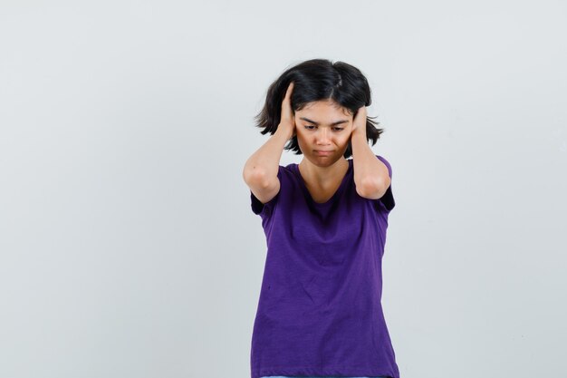 Niña cogidos de la mano en las orejas en camiseta y mirando molesto,