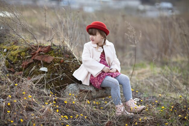 Niña con coletas en sombrero camina en el parque de primavera